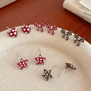 Polka dot bow and heart stud earring set in red and brown on a ceramic tray
