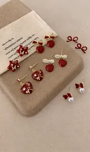 Close-up of heart and star red enamel earrings with pearls and crystals on fabric