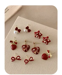 Detailed close-up of red enamel heart and bow earrings with crystals on fabric