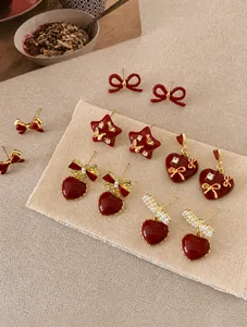 Detailed view of red enamel heart and bow earrings with gold plating and rhinestones