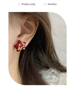 Close-up of red enamel star earring with golden butterfly and rhinestone accents