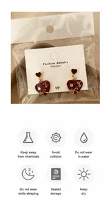 Detail of red heart earrings with golden bows and care instructions on display card