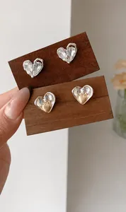 Detail of silver heart earrings with sparkling crystals and golden heart-shaped accents