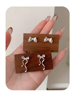 Detail shot of silver ribbon bow earrings featuring shimmering zircon crystals on wooden stand