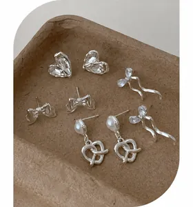 Close-up of four-pair silver earring set featuring hearts, bows, and pearl details