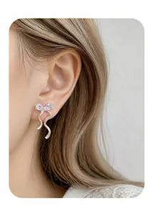 Detail shot of elegant silver bow earrings with sparkling cubic zirconia on model ear