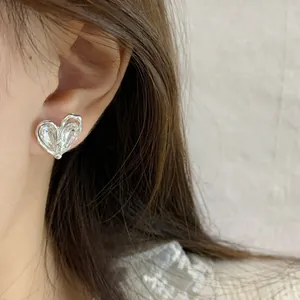 Elegant silver heart stud earring with clear crystal stone worn by a female model