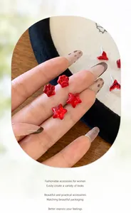 Nahaufnahme roter festlicher Stern- und Katzenpfoten-Ohrstecker in transparentem Design