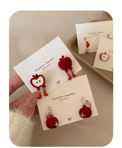Close-up of festive red flocked apple earrings with cute boot charms and silver needles