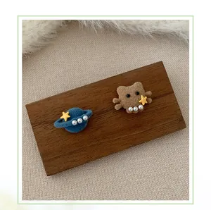 Detail von flauschigen Haarclips mit blauem Planeten, braunem Bär, Perlen und Sternen