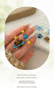 Detail von niedlichen asymmetrischen Bären- und Sternohrringen in der Hand auf Plüsch