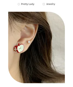Detail of red apple earring with star accent and rhinestone stud on female ear
