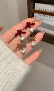 Dettaglio degli orecchini a fiocco in velluto con cuori argentati color bordeaux e marrone