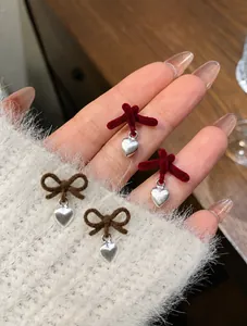 Dettaglio di orecchini a fiocco in velluto e cuore in metallo bordeaux e marrone