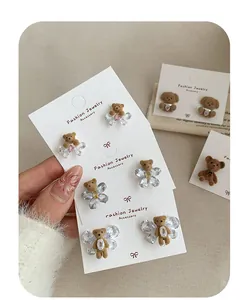Macro view of flocking bear earrings with crystal butterfly wings on jewelry card