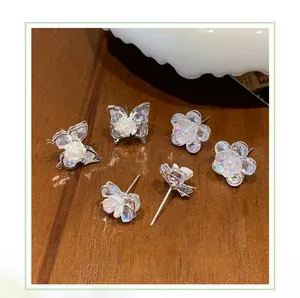 Detailansicht von Zirkonia-Schmetterling und Blumen-Ohrsteckern auf einem Holzhintergrund