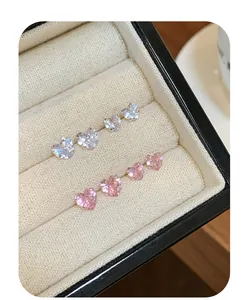 Détail des boucles d'oreilles en zircon rose et blanc en forme de cœur avec serti à griffes