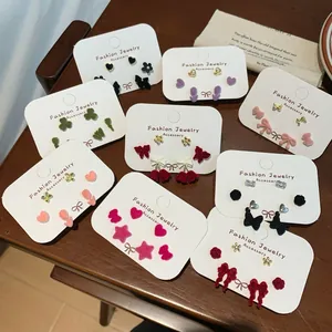 Colorful velvet bow and heart earring set with 925 silver needles on a rustic wood background