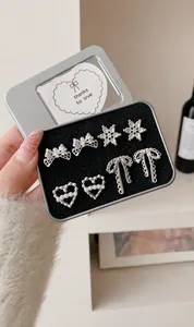 Set di orecchini a perno con fiocco e perla in una scatola regalo metallica