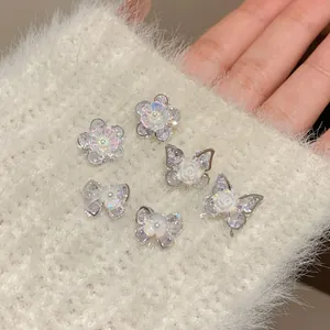Funkelnde Zirkon-Blumen- und Schmetterlingsohrringe auf einem weichen weißen Strickgrund