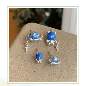 Dettaglio del set di orecchini a lobo con orsetto blu stellato e pianeta in argento