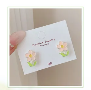 Detailed view of pink floral stud earrings with yellow center on jewelry display card