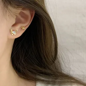 Elegant gold butterfly stud earrings with iridescent gemstones on model's ear