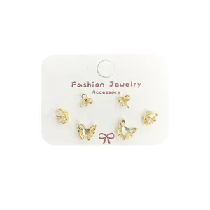 Three-pair gold butterfly earring set with heart stones on display card