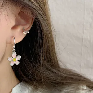 Pink daisy floral drop earrings with silver butterfly stud on woman's ear