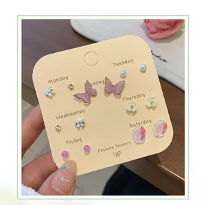 Close-up of seven pairs of butterfly and flower earrings set on a heart-shaped card