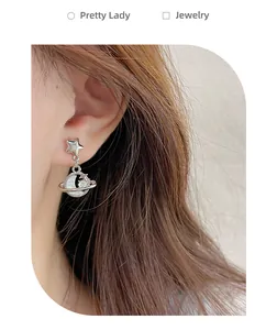 Macro shot of silver star and Saturn-style moon drop earring on ear for women