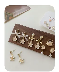Detailed macro view of gold-tone floral earrings with pearls and silk bows on a display