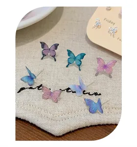 Detailed macro shot of assorted colorful butterfly stud earrings on textured fabric