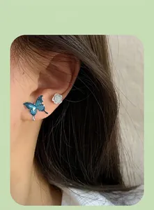 Detail of blue gradient butterfly and white 3D rose earring set worn by a model