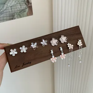 Pink cherry blossom earrings set with silver needles and floral resin petals on wood
