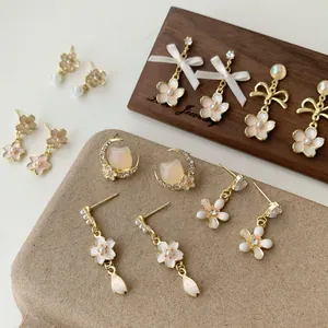 Pink cherry blossom earrings set with pearls and rhinestones on wood display
