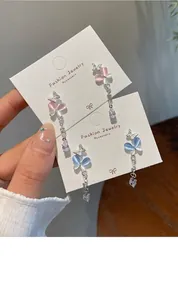 Detail of butterfly tassel earrings with cat-eye stones and crystal pendants