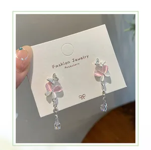 Detail of pink and white cat eye butterfly earrings with shimmering tassel charms