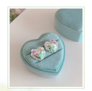 Detail of heart stud earrings with purple star enamel in a blue velvet jewelry box