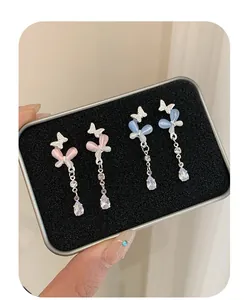 Detail of pink and blue butterfly earrings with cat eye stones and teardrop charms