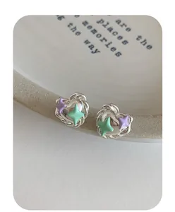Macro shot of silver heart earrings with purple and green star enamel details
