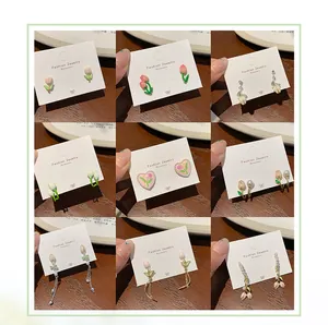 Collection of nine tulip themed stud earrings with pink and green enamel flower designs