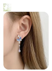 Detail of butterfly drop earring with blue stones and dangling teardrop zircon crystal