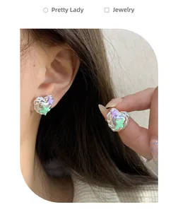 Detailed view of silver heart earrings with purple and green 3D stars on the ear