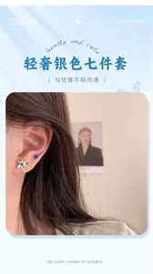 Detail of silver stud earrings set featuring blue floral gems on female model's ear