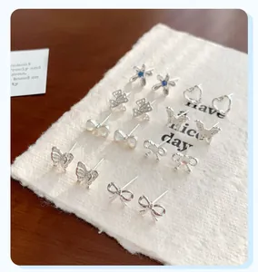 Detail view of silver earring set featuring butterfly and heart designs with blue gems