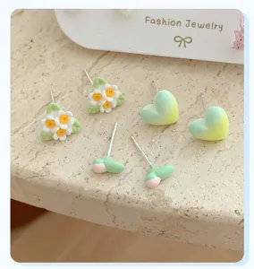 Macro shot of fresh floral and sprout stud earrings on a marble stone background