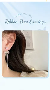 Detail of silver bow long tassel earrings with heart-cut stones worn by model