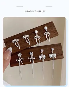 Detailed set of silver bow earrings with pearls, zircons and long tassel pendants