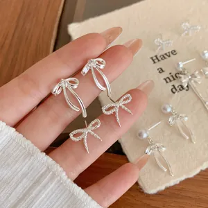 Silver bow earrings with long tassels and zircon accents in a sweet minimalist style